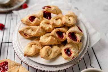 Krem peynirli ve ahududulu Kolacky. Reçelli ve kremalı hamur işi. Polonya Kolaczki kurabiyeleri, taze pişmiş.