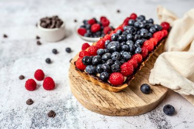 Fruit Tart full of Berries with chocolate and cream on cookie crust. European dissert.