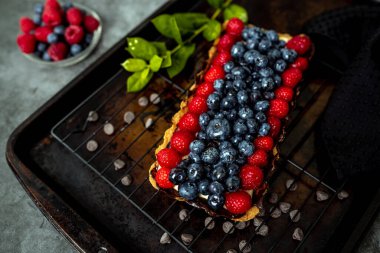 Fruit Tart full of Berries with chocolate and cream on cookie crust. European dissert.