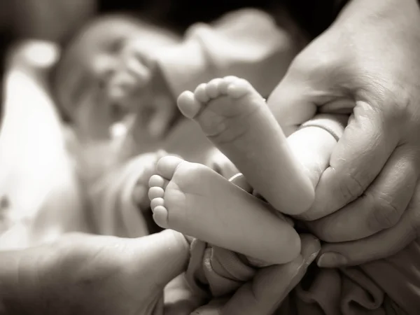 Pernas de um bebê nas mãos atenciosas — Fotografia de Stock