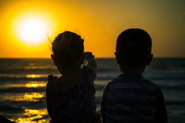 Enfants heureux sur un coucher de soleil au bord de la mer — Photo