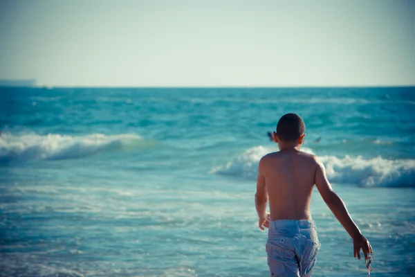 Jongen wandelen door de zee — Stockfoto