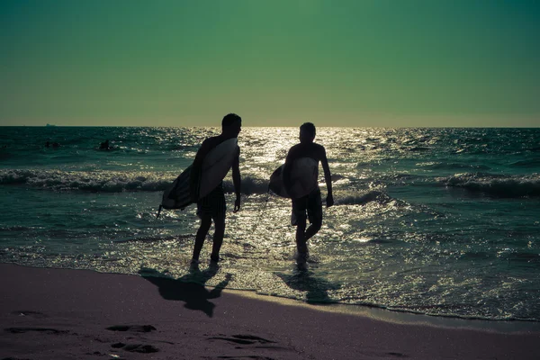 Siluetas de jóvenes surfistas en el mar —  Fotos de Stock