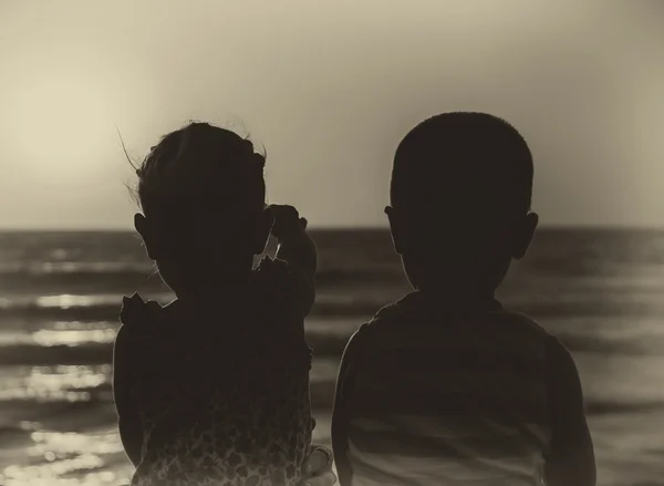 Enfants heureux sur un coucher de soleil au bord de la mer — Photo