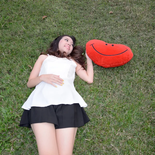 Donne che tengono grande amore cuscino a forma di cuore su erba verde — Foto Stock