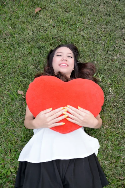 Women holding big love heart shape pillow on green grass — Stock Photo, Image