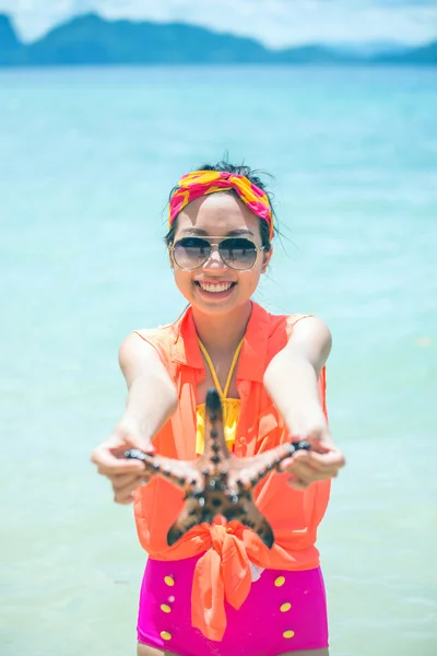 Young woman shows starfish during holiday at tropical island — Stock Photo, Image