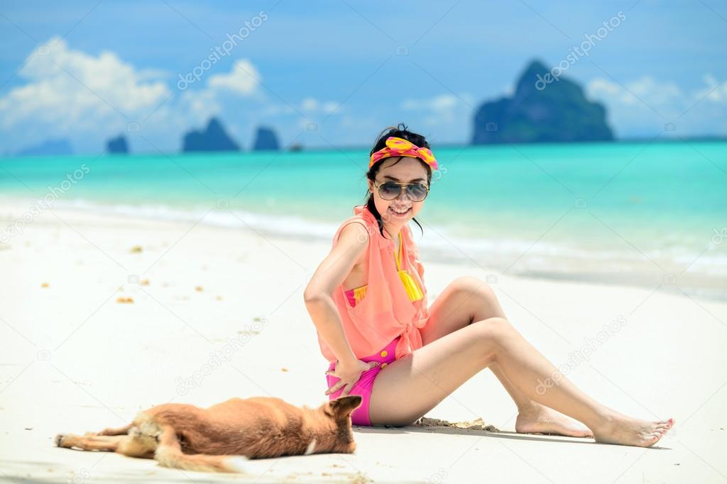 A portrait of beautiful asian woman on relaxing the beach with dog