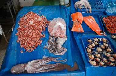 Şili Valparaiso 'daki yerel markette taze ahtapot, karides, somon filetosu ve deniz tarağı yakaladım. Pasifik Okyanusu 'ndan taze deniz ürünleri mavi arka planda market tezgahında. Şili 'de çeşitli deniz ürünleri