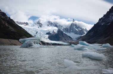 Buzdağlarından ayrılan Laguna Torre Gölü. Cerro Torre dağının bulutlar ve Torre buzullarındaki panoramik manzarası. Bir gün El Chalten, Patagonya, Arjantin 'den Laguna Torre' ye yürüyüş