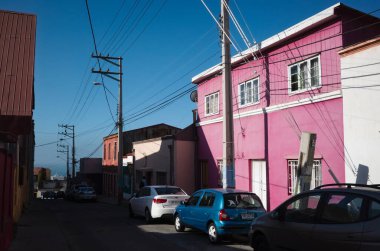 Valparaiso, Şili - Şubat 2020: Tepedeki Valparaiso sokaklarında pembe bina. Pasifik Okyanusu uzaklıktan görülebilir. Pembe renge boyanmış eski tarihi bina. Sokakta park etmiş arabalar.