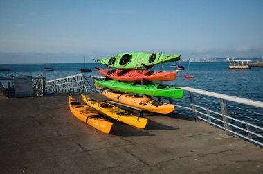 Valparaiso, Şili - Şubat 2020: Pasifik Okyanusu 'nun Bahia de Valparaiso körfezindeki Muelle Baron rıhtımında yığılmış birkaç renkli kano. Ufuktaki Vina del Mar şehrinin küçük yatları ve manzarası