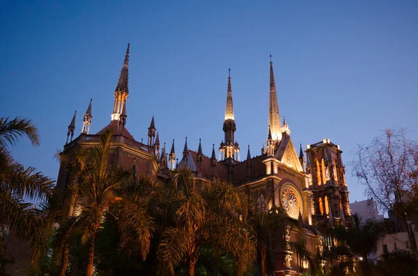 Catholic church in neo gothic architectural style with spires called Iglesia del Sagrado Corazon de Jesus also known as Iglesia de los Capuchinos. Gothic style illuminated church, palms in foreground