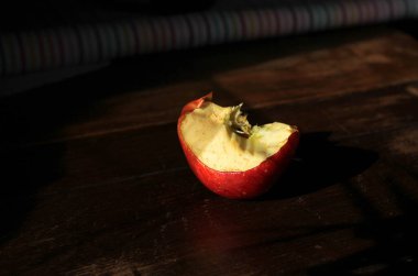 Isırılmış elma, siyah ahşap arka planda bir dal. 