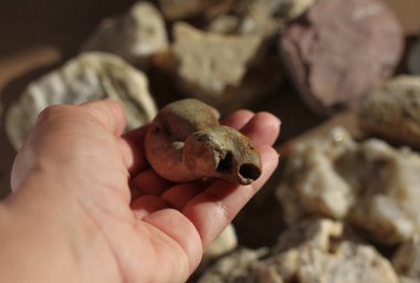 Bulanık ışık arka planında bir kadının elinde duran mineral taşı. 