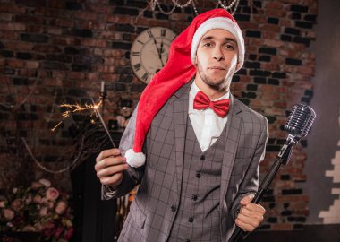 Noel Baba şapkalı ve elinde maytap olan bir adam.