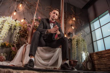 Genç yakışıklı adam salıncakta salıncakta oturuyor.