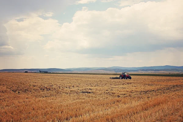 Tractor working in the field on a cloudy day — Stock Photo, Image