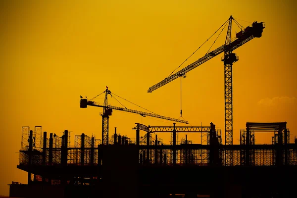 Guindastes de construção industrial e silhuetas de construção — Fotografia de Stock