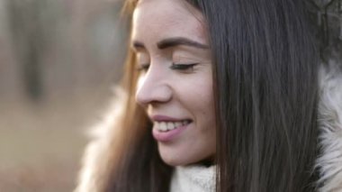 Kahverengi gözlü güzel bir esmerin video portresi. Kışlık elbiseli genç bir kız. Çekici kadın mutlu ve gülümsüyor.