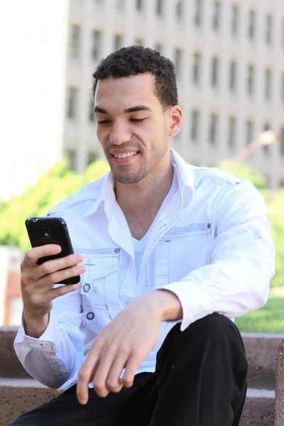 Handsome young man in white shirt chatting on mobile phone — Stock Photo, Image