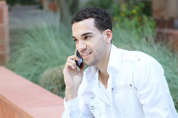Serious young man in white shirt talking on mobile phone — Stock Photo, Image