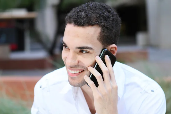 Handsome young man smiling and talking on mobile phone outdoor — Stock Photo, Image