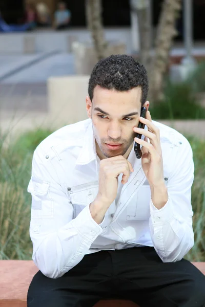 Vážný mladý muž v bílé košili na mobilním telefonu — Stock fotografie