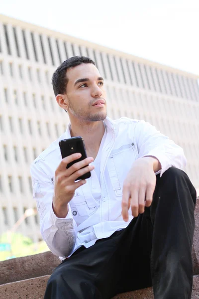 Knappe jonge man in het wit overhemd chatten op mobiele telefoon Stockfoto