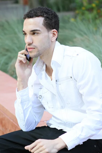 Jeune homme sérieux en chemise blanche parlant sur téléphone portable Photo De Stock