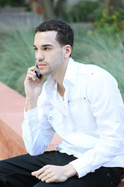 Jeune homme sérieux en chemise blanche parlant sur téléphone portable Images De Stock Libres De Droits