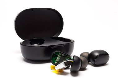 Kırık çalışmayan, parçalanmış kablosuz kulaklıklar beyaz arka planda siyah renkte. Mikro elektronik ve cihazların onarımı