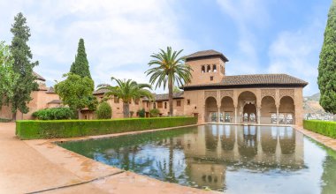 Alhambra Granada İspanya - 09 14 2021: Partal Palace veya Palacio del Partal, İspanya 'nın Granada kentindeki Alhambra Kalesi kompleksi içinde yer alan bahçeler ve su gölü etrafında saray manzarası