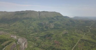 Tropikal bir arazinin hava aracı görüntüleri, orman ve dağlarla kumbira orman rezervleri, küçük köy ve Conda, Sumbe, Angola 'daki devasa jeolojik kaya elementleri....