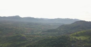 Tropikal bir arazinin hava aracı görüntüleri, orman ve dağlarla kumbira orman rezervleri, küçük köy ve Conda, Sumbe, Angola 'daki devasa jeolojik kaya elementleri....