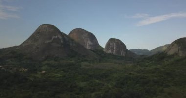 Tropikal bir arazinin hava aracı görüntüleri, orman ve dağlarla kumbira orman rezervleri, küçük köy ve Conda, Sumbe, Angola 'daki devasa jeolojik kaya elementleri....