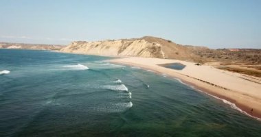 Sörfçülerin plaja, sakin suya ve jeolojiye ve Angola 'nın tipik bitki örtüsüne bakış