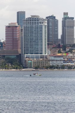 Luanda Angola - 10: 13: 2021: Şehir merkezindeki Luanda şehrinde, modern gökdelenler binaları, körfez, marjinal ve merkezi binalar, Angola körfezindeki geleneksel küçük teknede balıkçı,