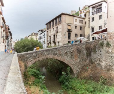 Granada İspanya - 09: 14 2021: Darro Caddesi, Paseo de los tristes, Cabrera Köprüsü, turist ziyaretleri ikonik ve pitoresk cadde, arka plan olarak Alhambra kalesi, Granada, İspanya