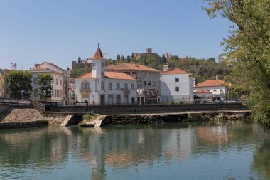 Tomar Portugal - 08 09 2022: Tomar City şehir merkezinde, Nabao nehri, eski şehir köprüsü, Poucho parkı ve ikonik Tomar Kalesi ve İsa Manastırı ile
