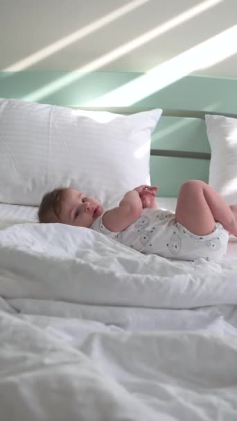 Mały chłopiec w pielusze leży na białej pościeli na dużym łóżku — Wideo stockowe
