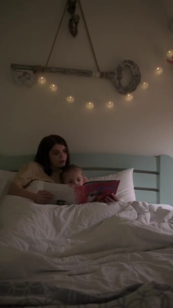 Madre e hija leyendo un libro antes de acostarse — Vídeo de stock