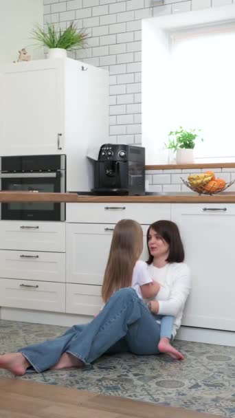 Μια μητέρα με μια ξανθιά κόρη κάθεται και μιλάει στο πάτωμα της κουζίνας. — Αρχείο Βίντεο