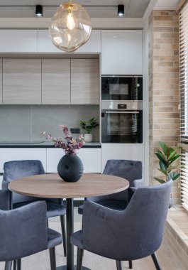 Pencere kenarındaki mutfak ve yemek masası modern bir çatı katı tarzında.