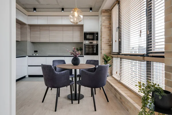 Pencere kenarındaki mutfak ve yemek masası modern bir çatı katı tarzında.