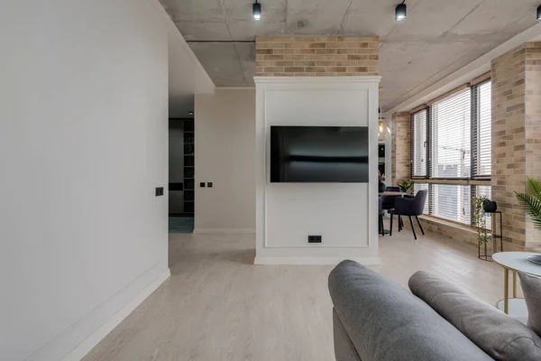 Interior in a modern style and a view of the TV and part of the kitchen near the large windows with blinds — Stockfoto