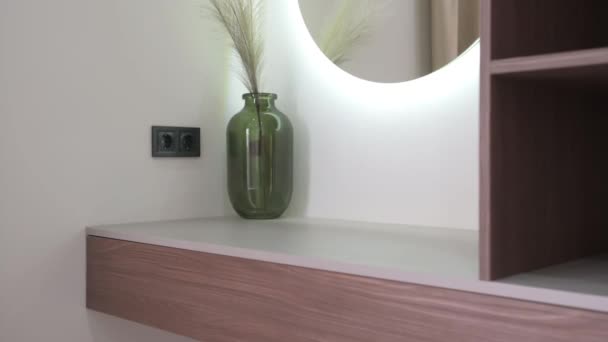 Empty wooden shelf with glowing mirror and green glass vase — Stockvideo