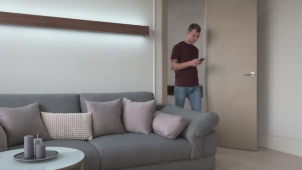 Interior de estilo escandinavo con un gran sofá gris un hombre sale de la habitación — Vídeo de stock