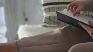 Beyaz iç mekanda, kız bir kitap okuyor ve dikiz aynasının sayfalarını çeviriyor. Yüksek kaliteli FullHD görüntüler