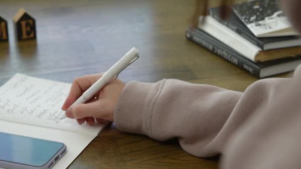 Close-up on the hands of a student girl who writes something in a notebook — Vídeo de Stock